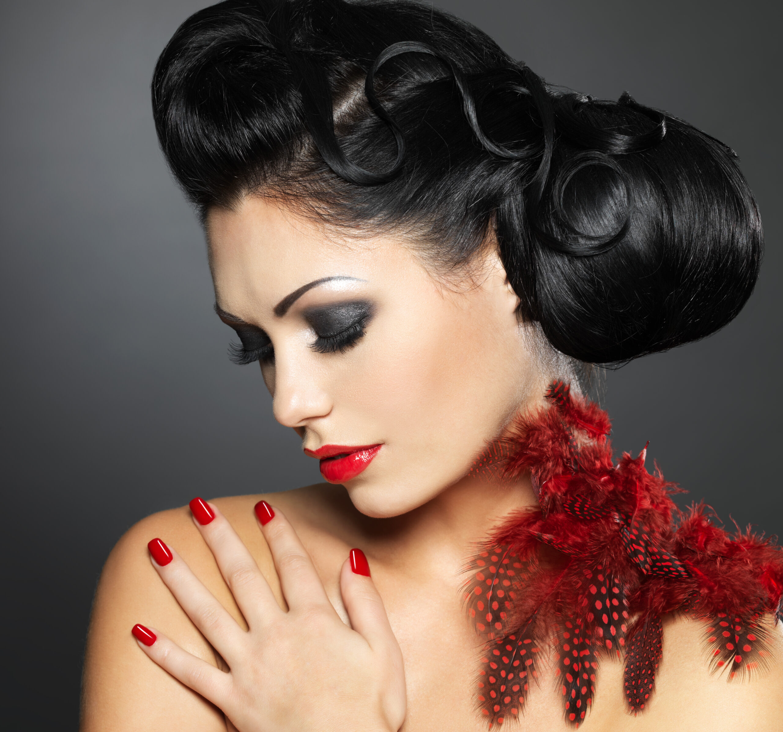 Fashion young woman with red nails, creative hairstyle and makeup - Model posing in studio